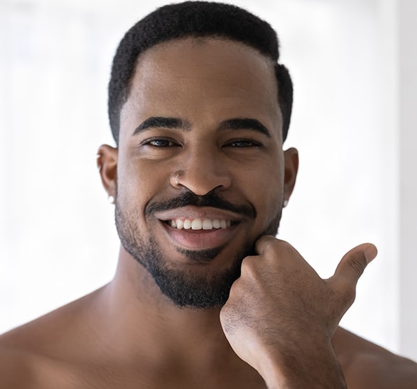 Head shot portrait smiling African American man touching beard